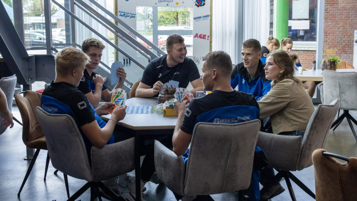 Spelers van Blauw Wit spelen samen een kaartspel in de kantine